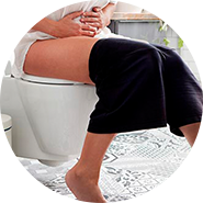 mulher sentada numa sanita em visiviel desconforto