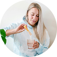 Senhora a colocar um suplemento em p&oacute; num copo de &aacute;gua